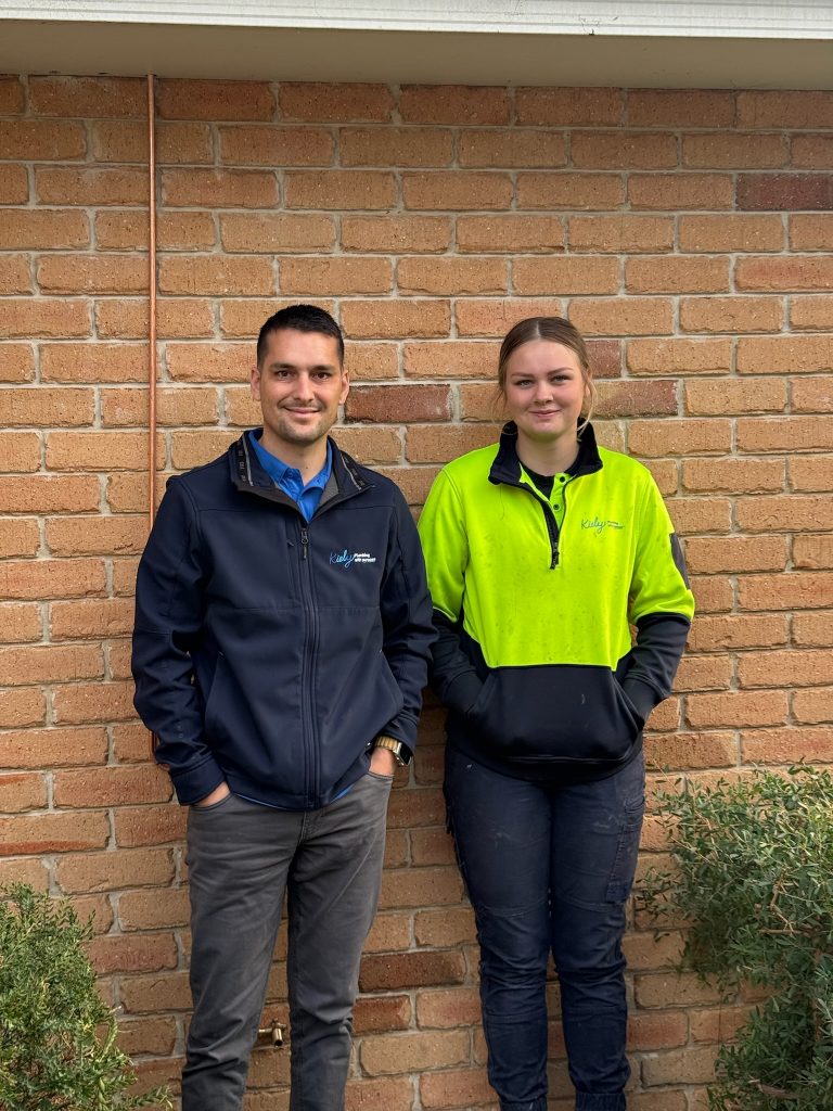 Sam Kiely and Isabella standing together in a trades uniform.